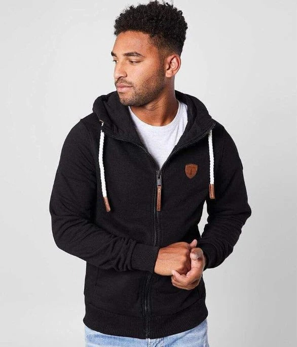 Man wearing a black hoodie with a brand logo on a light gray background